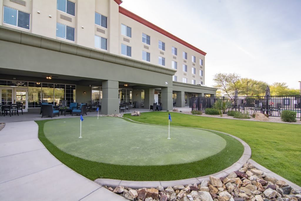 A hotel with an outdoor putting green surrounded by a landscaped lawn.