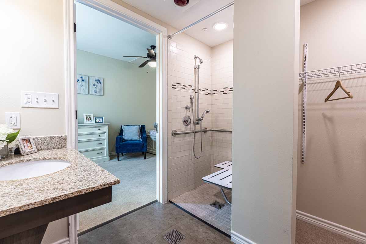 A modern, accessible bathroom featuring a walk-in shower with a built-in bench and sleek fixtures.