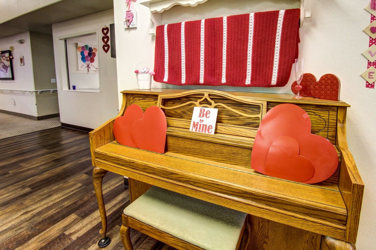 A piano decorated with red heart-shaped cushions and Valentine's Day-themed decor.