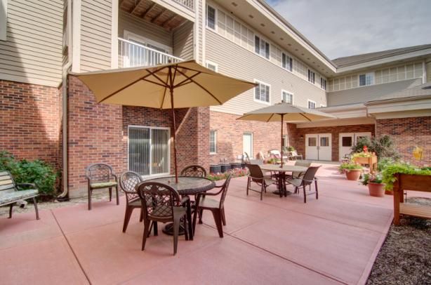 A spacious outdoor patio area with tables, chairs, and umbrellas in front of a building.