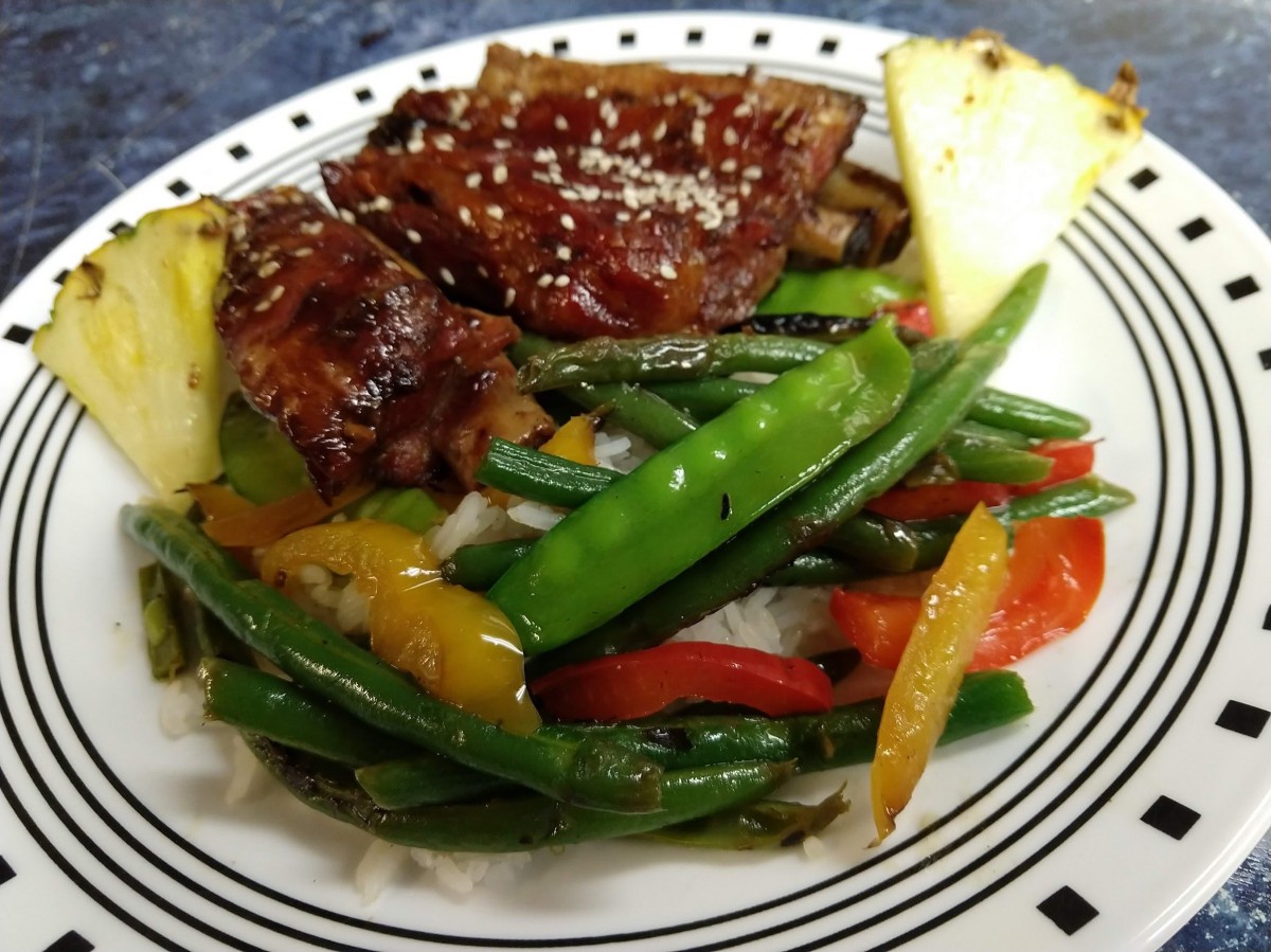A delicious plate featuring steak, colorful vegetables including green beans and peppers, and a slice of pineapple.