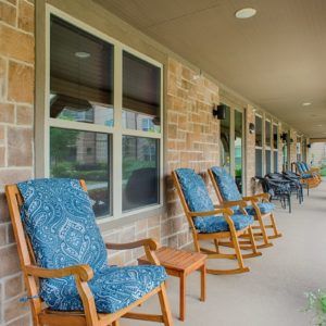 A cozy porch with wooden rocking chairs and blue patterned cushions.