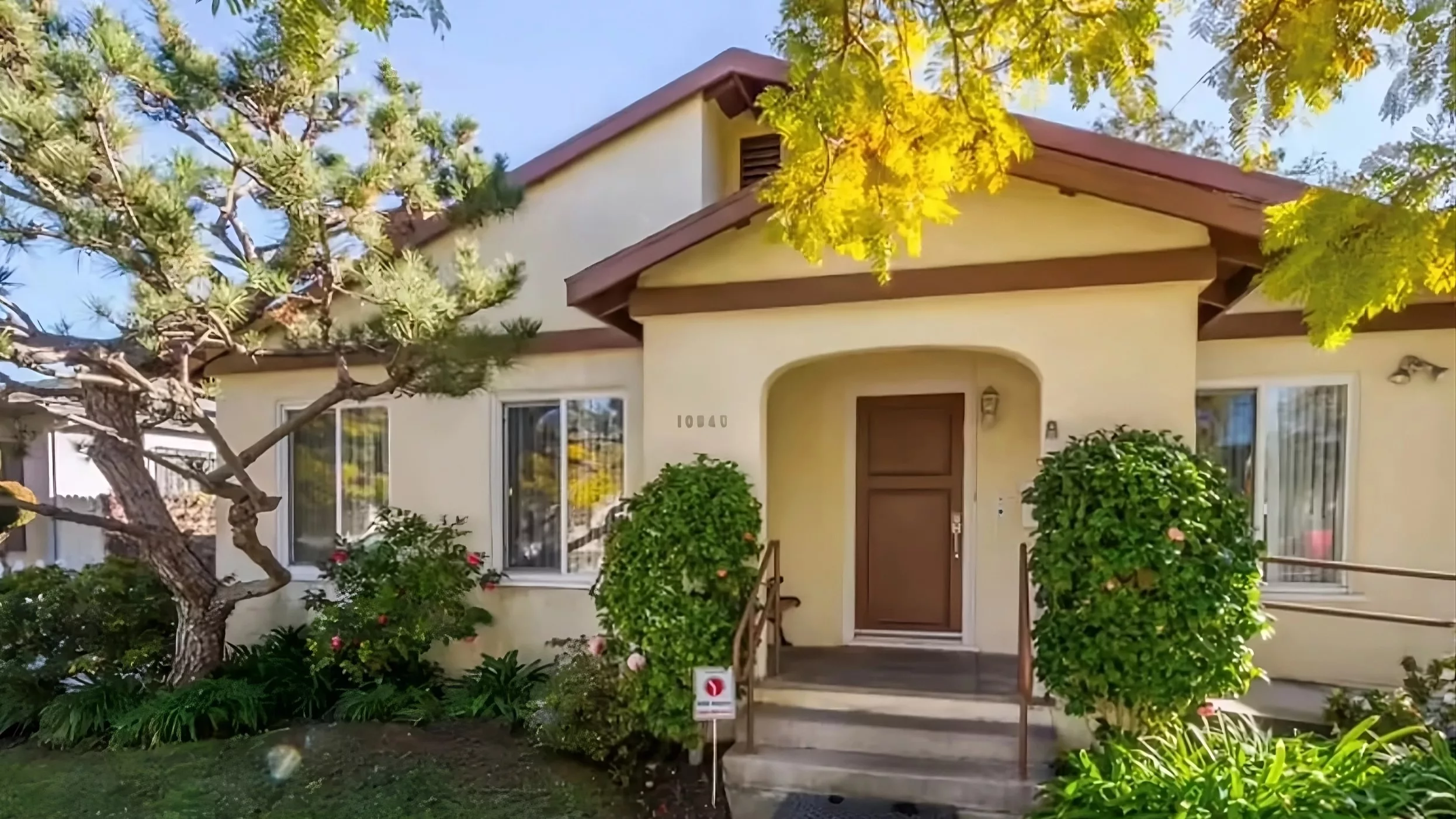 A charming residential house with a wooden front door, surrounded by greenery.