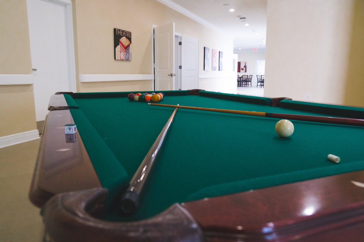 A pool table set up for a game with cue sticks and billiard balls in an indoor game room.