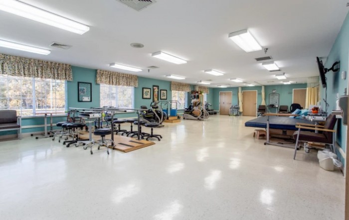 A spacious physical therapy room equipped with exercise machines and therapy beds.