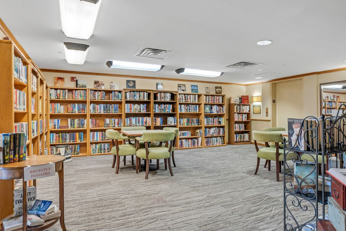 A quiet library space with bookshelves, tables, and chairs for reading.
