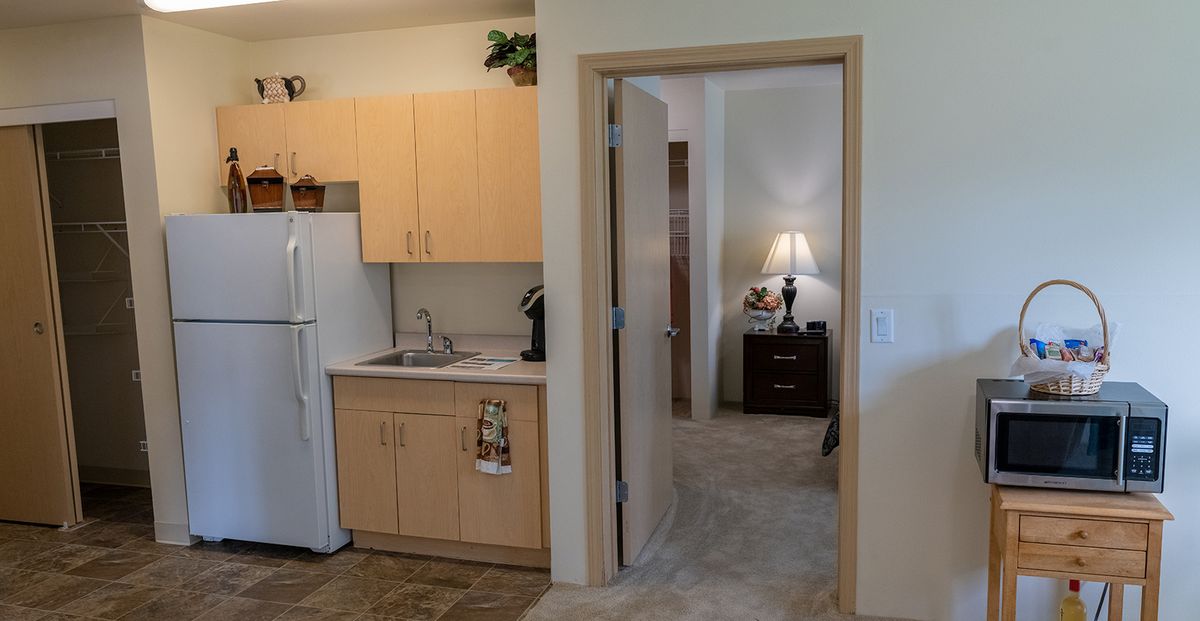 A cozy apartment interior featuring a small kitchen area and adjoining room.