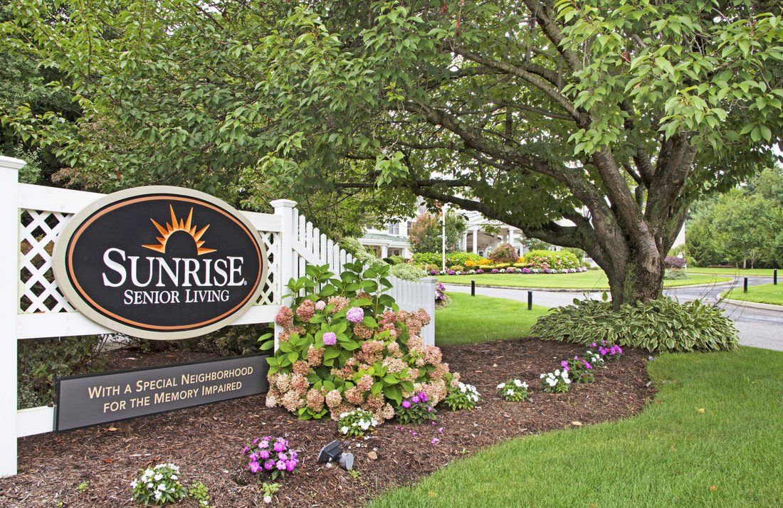 A scenic view of a landscaped garden with a sign reading 'Sunrise Senior Living'.