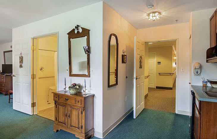 A cozy hallway with a dresser and mirrors, leading to other rooms.
