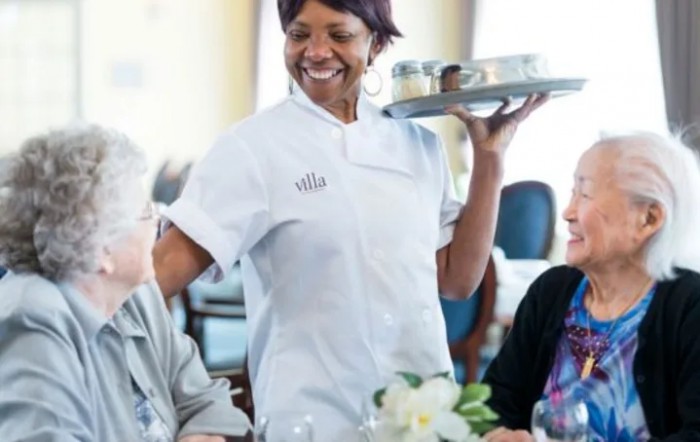 A smiling waitress in uniform serving customers at a restaurant.