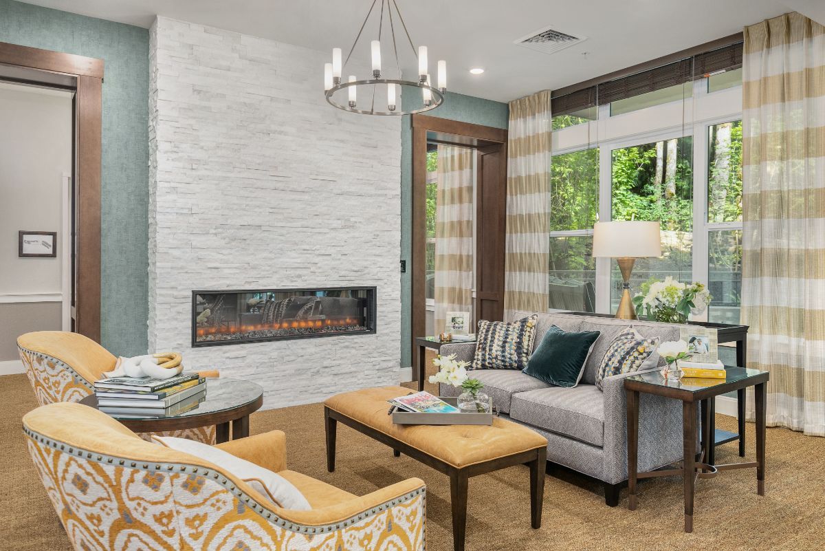 A cozy living room with a modern fireplace, elegant chandelier, and comfortable seating.