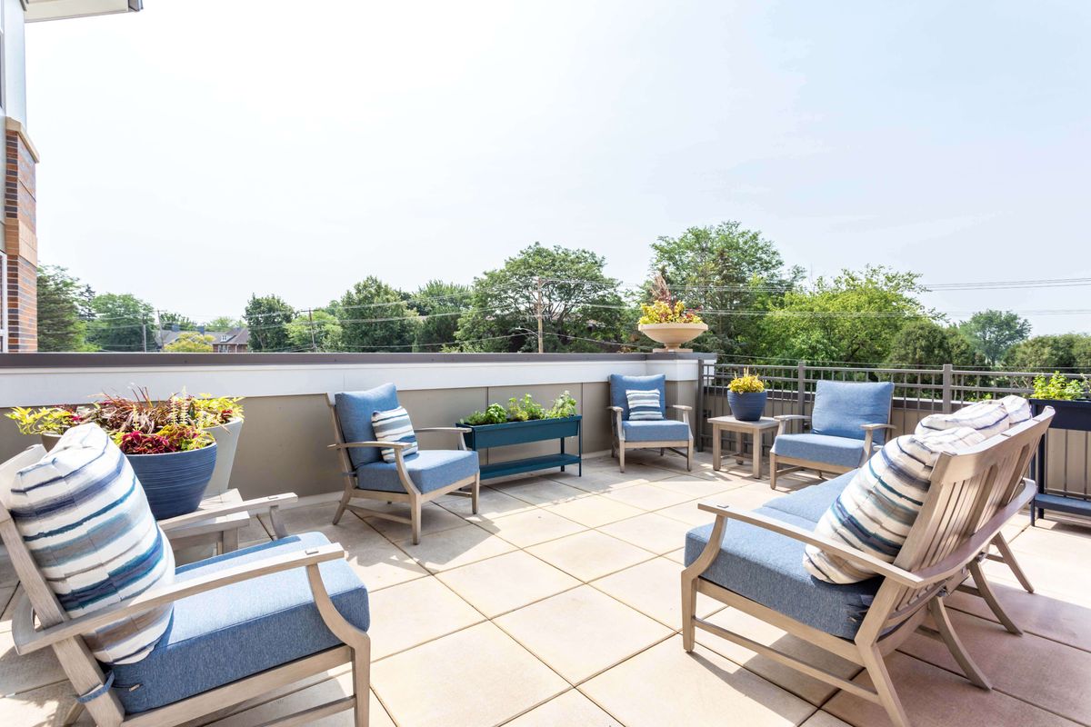 A sunny outdoor patio with comfortable seating and greenery.