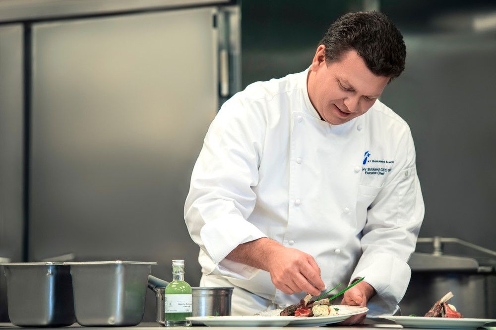 A chef expertly preparing a dish in a professional kitchen.