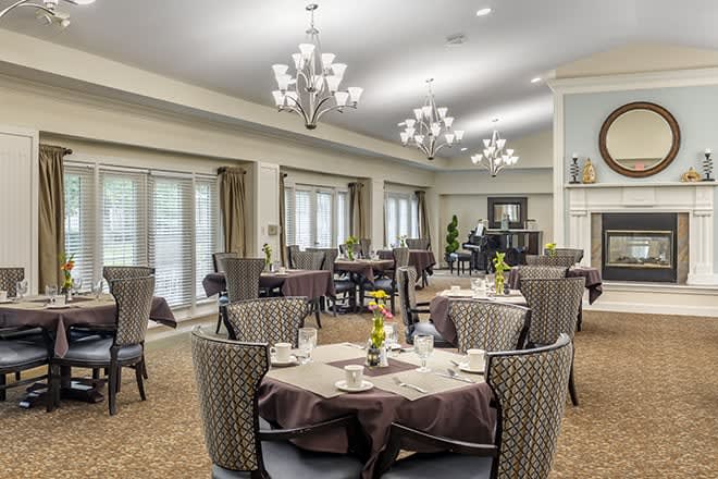 An elegant dining room with neatly arranged tables and chairs, adorned with chandeliers.
