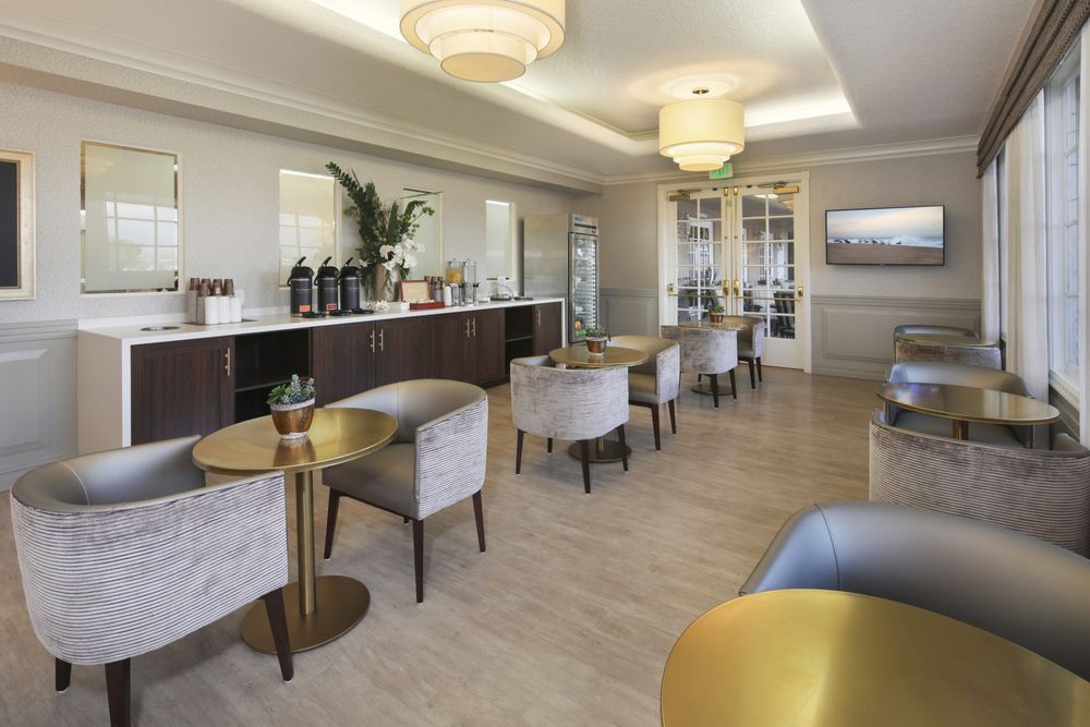 A modern and stylish lounge with comfortable seating, tables, and a coffee station.