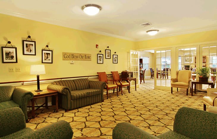 A cozy living room with yellow walls, featuring a sofa, chairs, and a patterned carpet.