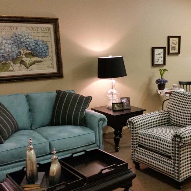 A cozy living room featuring a teal sofa, patterned armchair, and ambient lighting.
