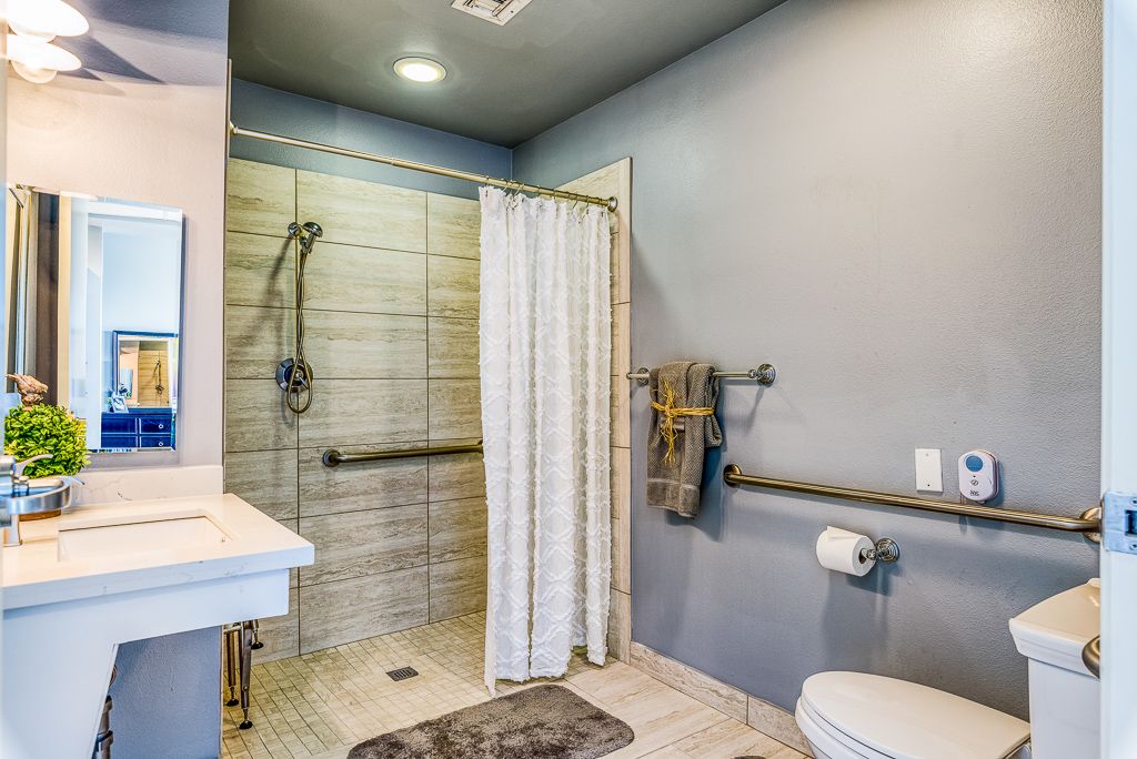 A modern, accessible bathroom with grab bars and a walk-in shower.