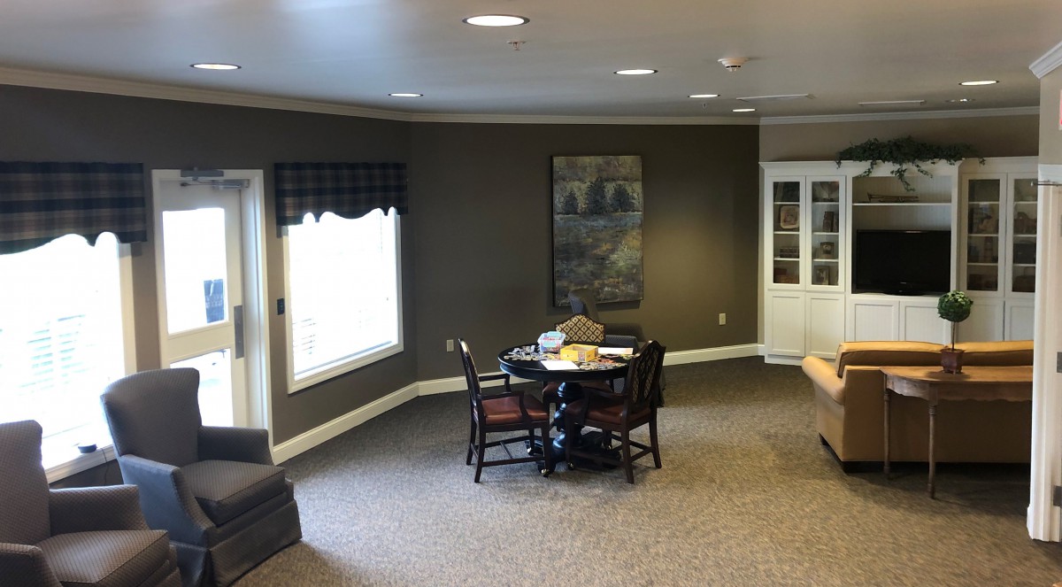 A cozy living room with a table and chairs, featuring a large window and wall art.