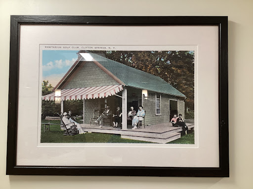 A vintage photograph of a family gathered on the porch of their house, surrounded by nature.