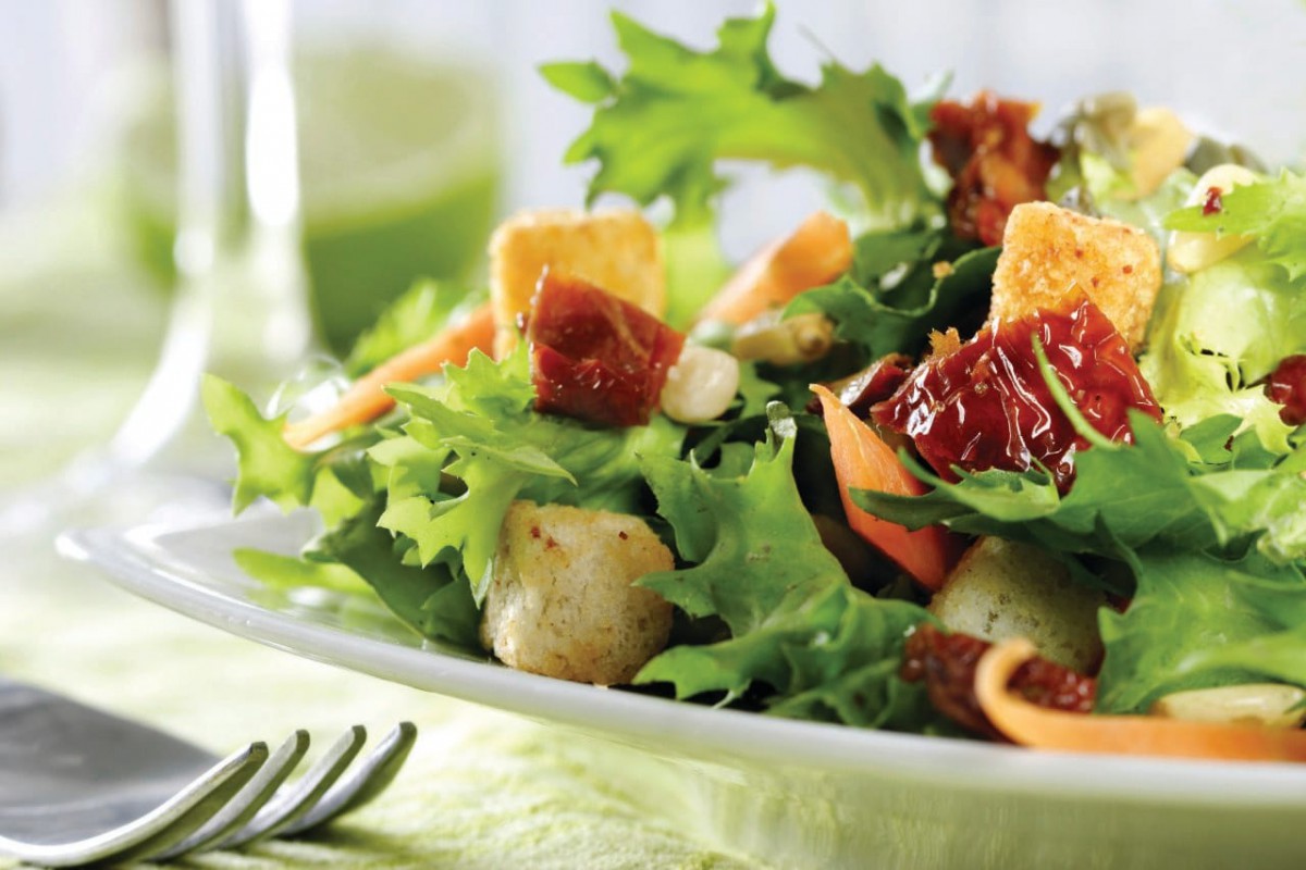 A vibrant salad featuring fresh greens, croutons, and sun-dried tomatoes.