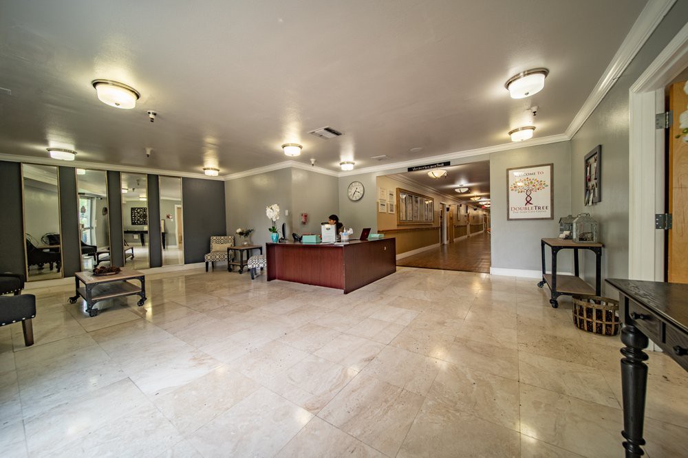 A spacious and modern reception area with a desk, chairs, and a hallway in the background.