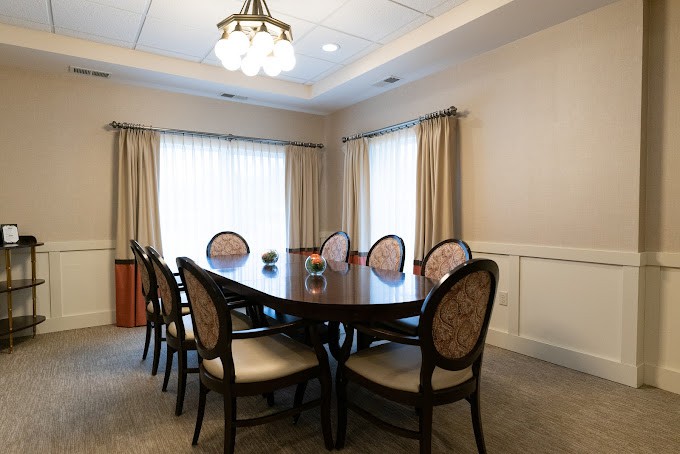 A well-furnished conference room featuring an oval table surrounded by chairs and illuminated by ceiling lights.