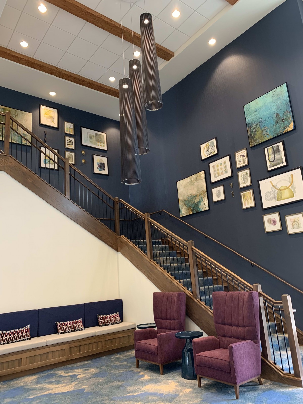 A modern lobby featuring a gallery wall, staircase, and comfortable seating area.