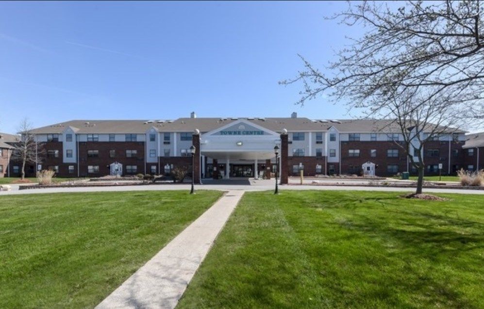 A large residential building with a well-maintained lawn and central entrance.