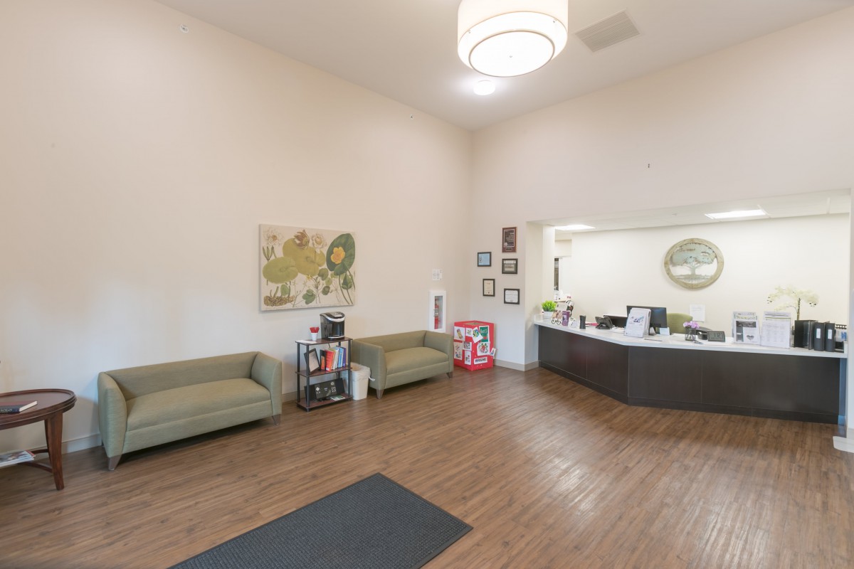 A spacious waiting room with sofas, artwork, and a reception desk.