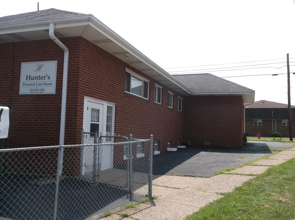 A brick church building with a chain-link fence and a small parking area.