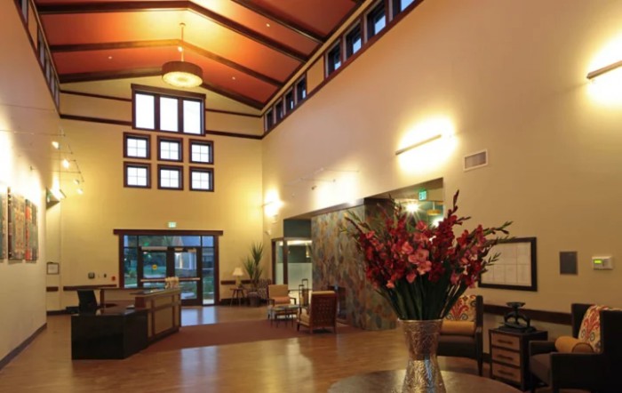 A modern and spacious lobby with high ceilings, stylish lighting, and floral arrangements.