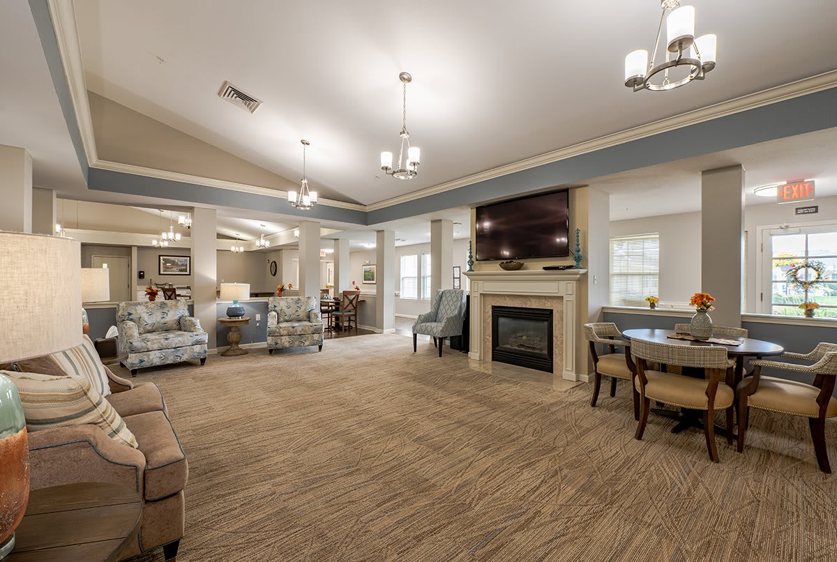 A spacious and modern living room featuring a central fireplace, elegant furniture, and ceiling lights.