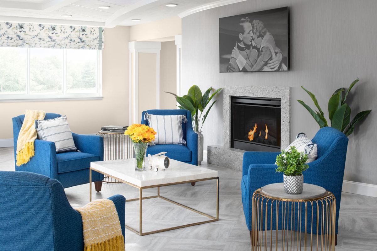 Modern living room with blue chairs and a cozy fireplace.