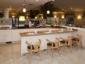 A modern cafe interior with a long counter and wooden chairs.