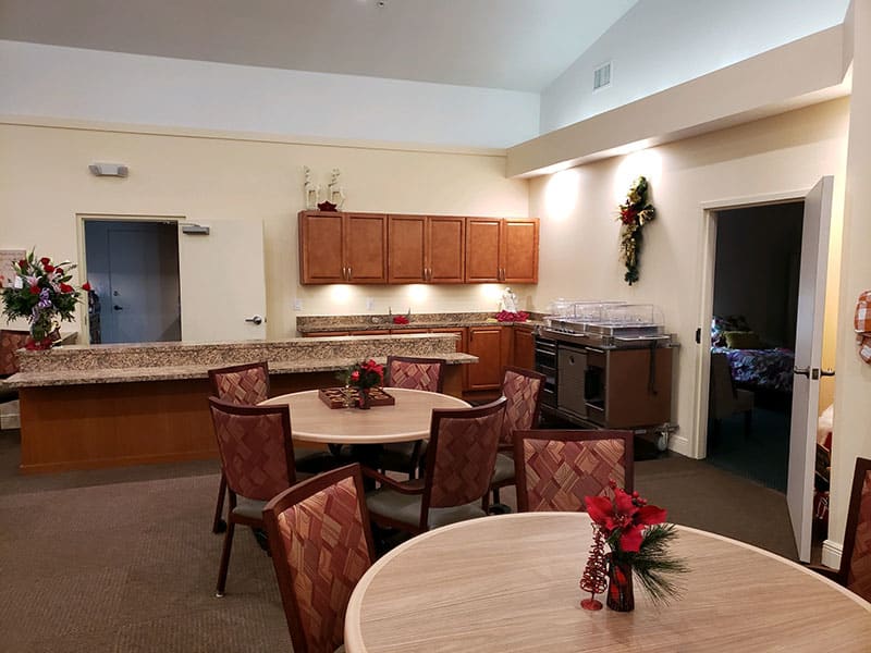 A cozy kitchen and dining area with round tables, chairs, and wall decorations.