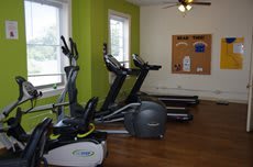 A small gym with treadmills and an elliptical machine in a bright, well-lit room.