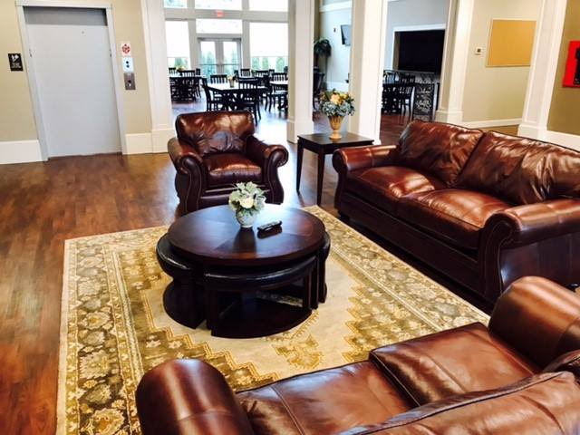 A cozy living room with leather sofas, a round coffee table, and a patterned carpet on a wooden floor.