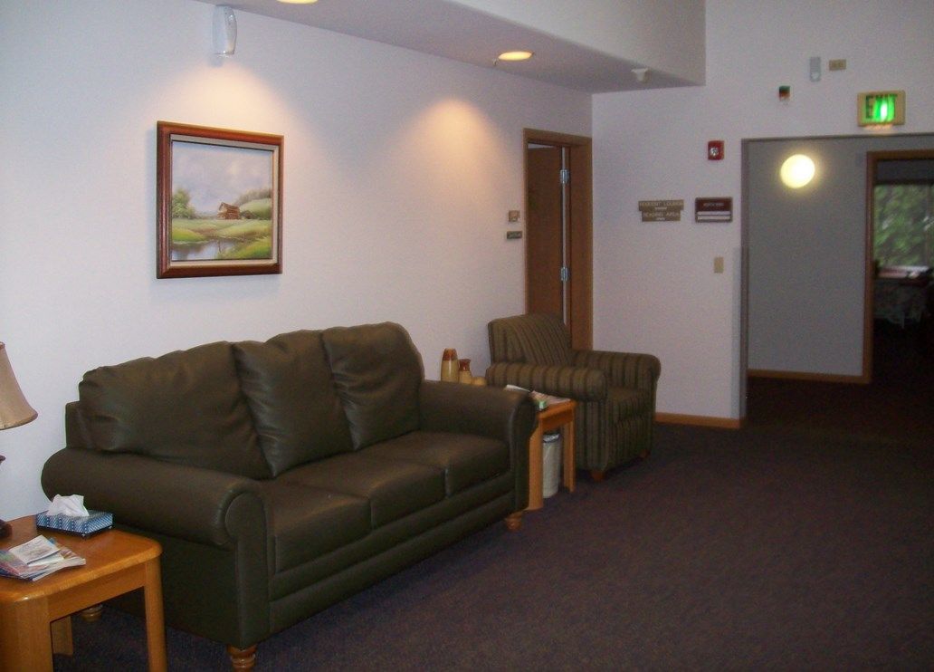 A cozy lobby area with a sofa, armchair, and wall painting.