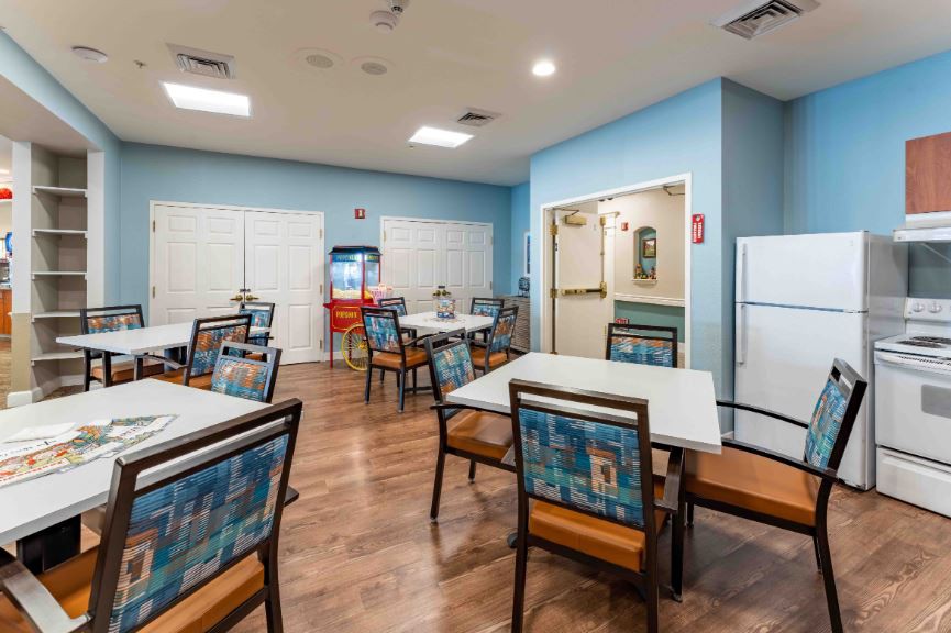 A cozy indoor dining area featuring tables and chairs, with blue walls and wooden flooring.