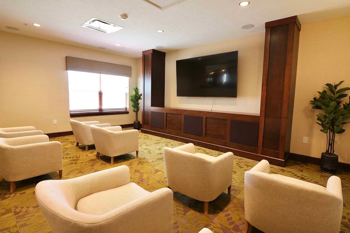A cozy lounge area with white chairs and a large TV.