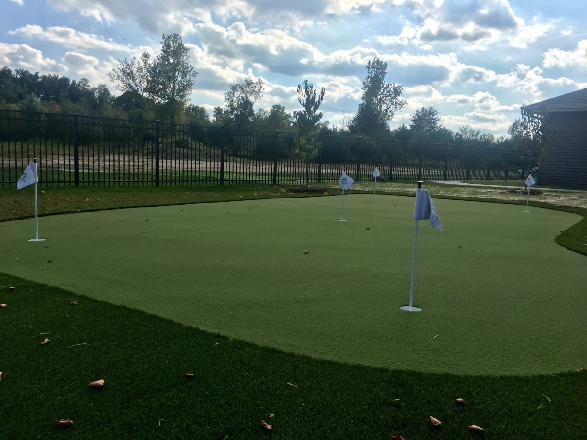 A peaceful view of a golf putting green under a cloudy sky.