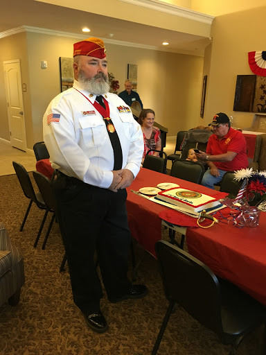 A man in a military uniform stands proudly at an indoor event, ready to participate in a ceremony.