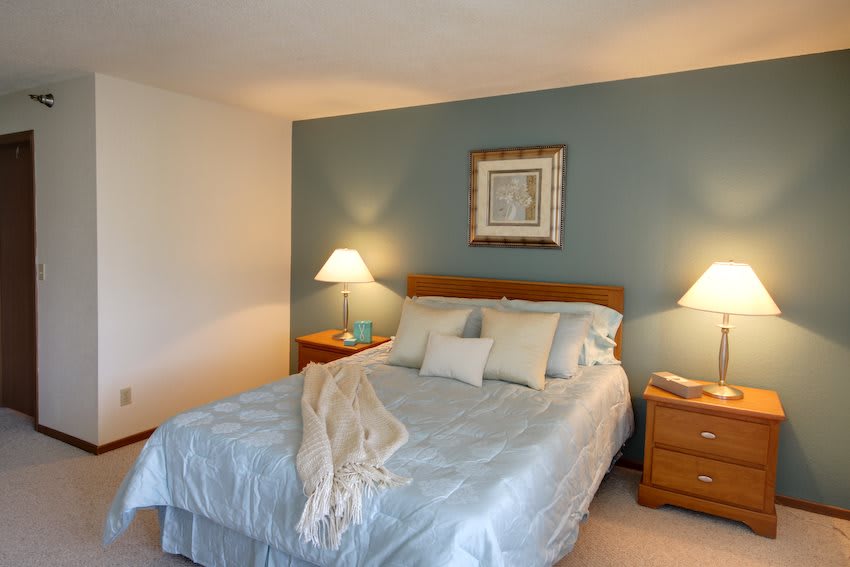 A cozy bedroom with a neatly made bed, two nightstands, and soft lighting.