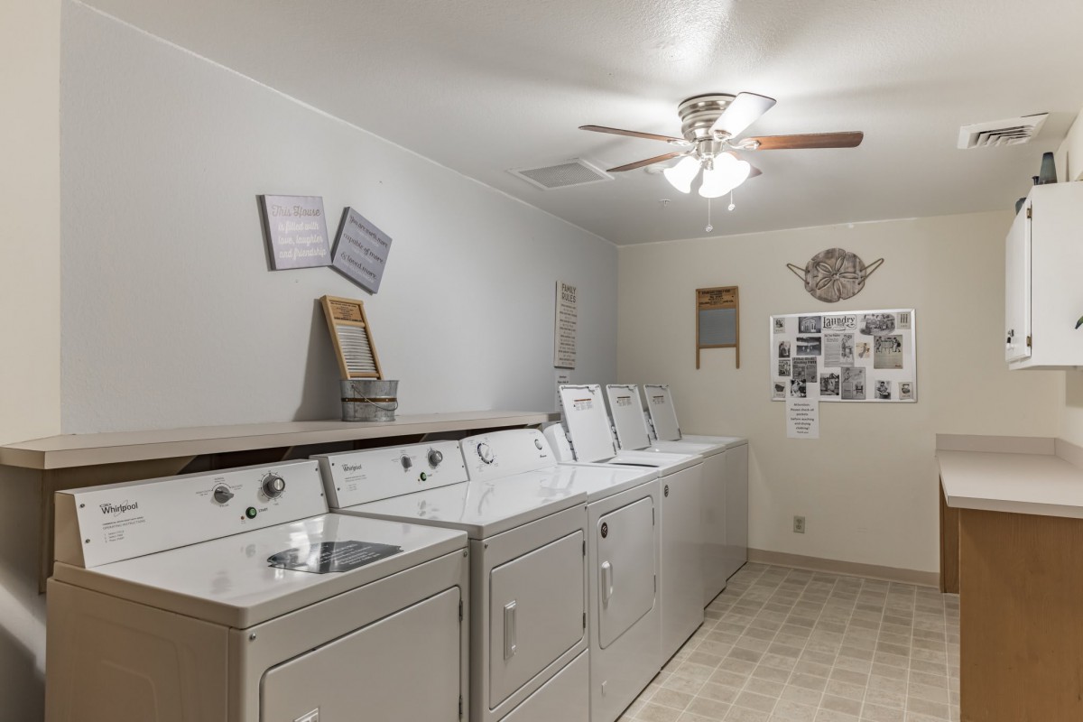 A clean and tidy laundry room with multiple washing machines and dryers.