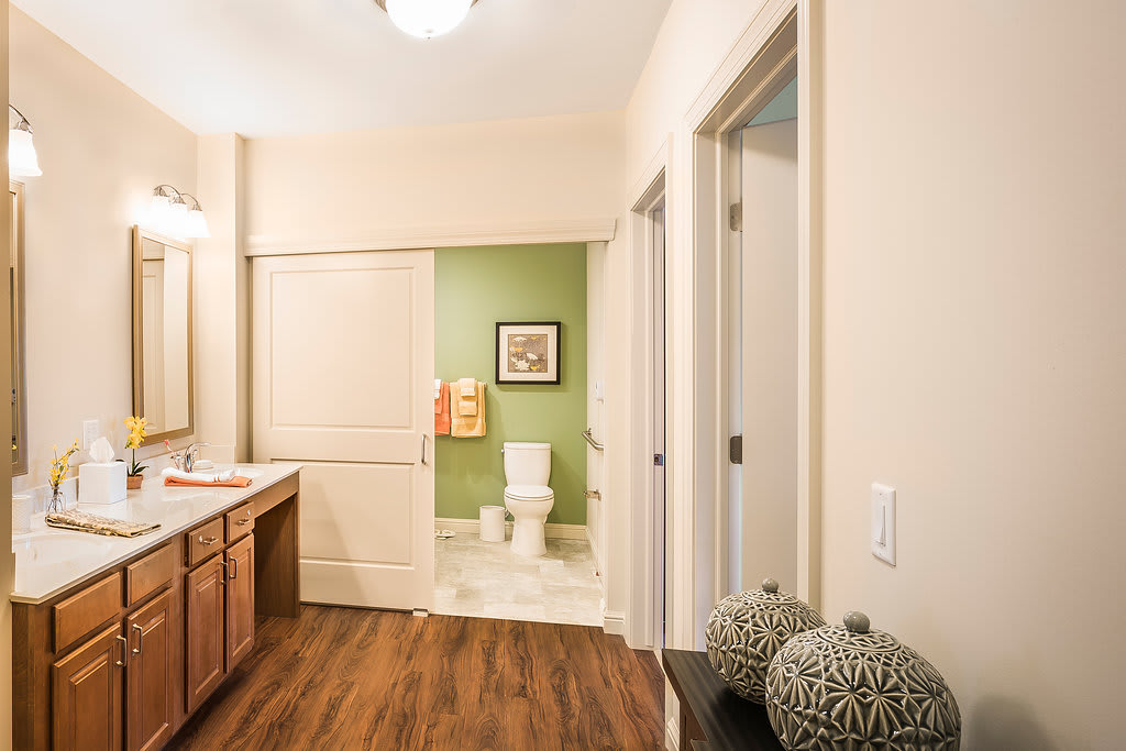A modern bathroom interior with a wooden floor and green accent wall.