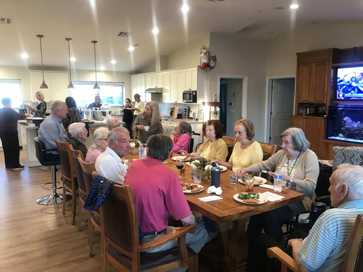 A group of people enjoying a meal together in a kitchen setting.