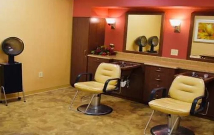A salon interior with chairs, mirrors, and hair dryers on the counter.
