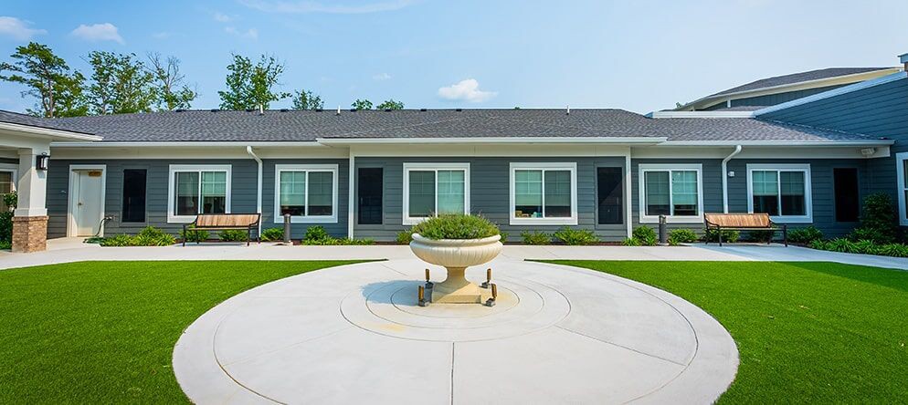 A modern residential building with a neatly manicured lawn and circular concrete pathway.