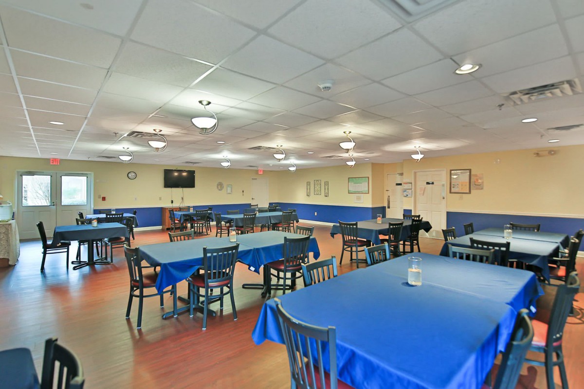 A spacious dining area with blue tablecloths and neatly arranged tables and chairs.